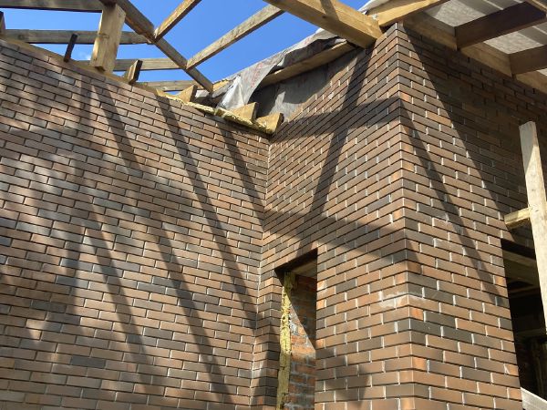 Каркас крыши, кирпичные стены коттеджа